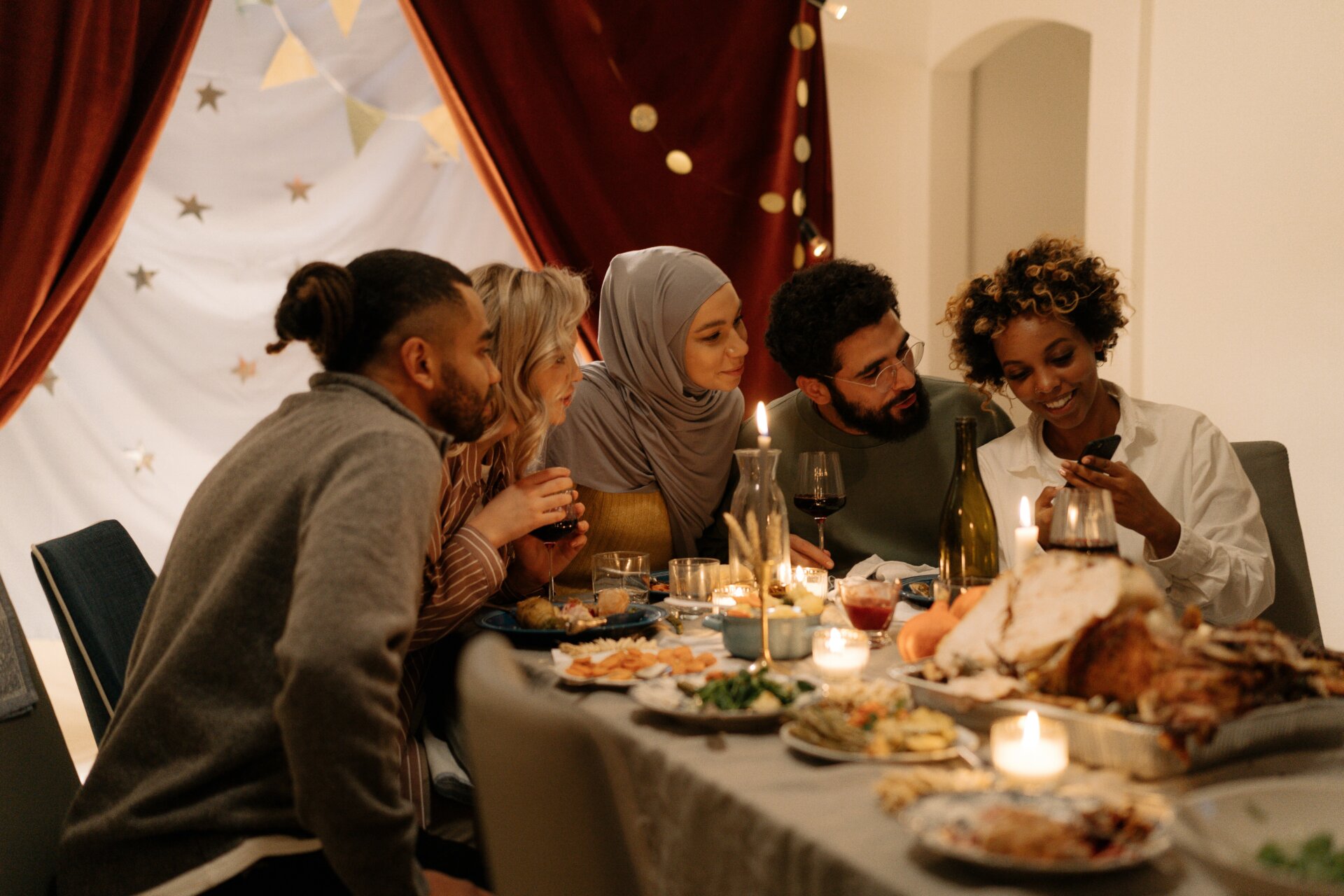 Group of friends gather around a dinner table engaged in conversations worth having after participating in the monday kickstarters holiday series