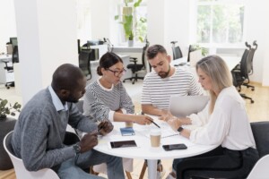 Four colleagues sit around a table engaging in meaningful and productive dialogue during a Conversation Bootcamp exercise.